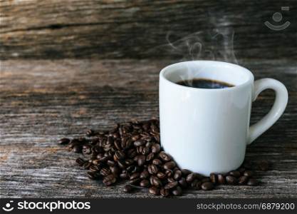 Coffee beans in green bowl on old wood background with sunlight