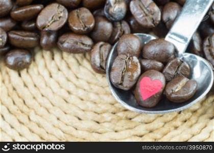 Coffee beans in metallic spoon and background with clipping path of heart shape, easy to change or adjust heart shape color.&#xA;