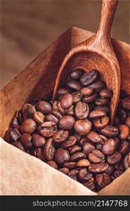 Coffee beans in paper bag with wooden scoop closeup. Coffee beans in paper bag with wooden scoop