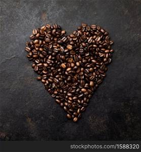 Coffee beans in shape of heart on dark rustic background, flat lay