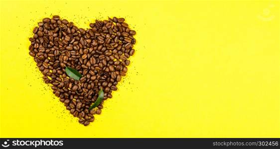 Coffee beans in shape of heart on yellow background. Coffee beans in shape of heart, flat lay, top view