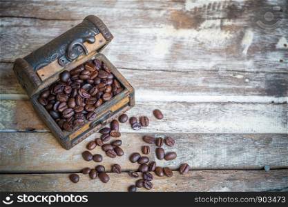 Coffee beans in the old chest on old wooden table background.