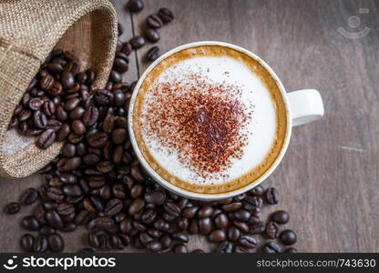 Coffee beans in the sack with a coffee cup on wooden table background.