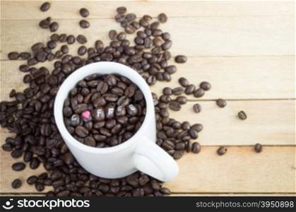 Coffee beans in white mug and wood background&#xA;