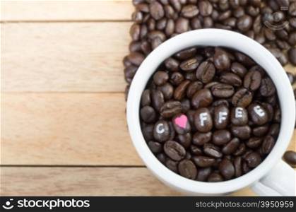 Coffee beans in white mug and wood background&#xA;