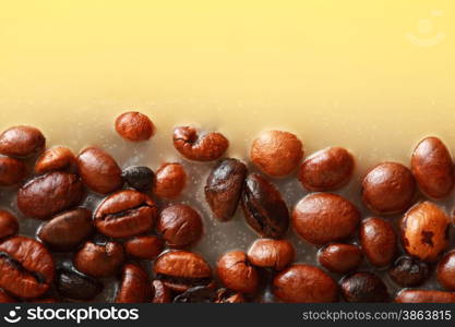 Coffee beans in yellow wax as background with space for text