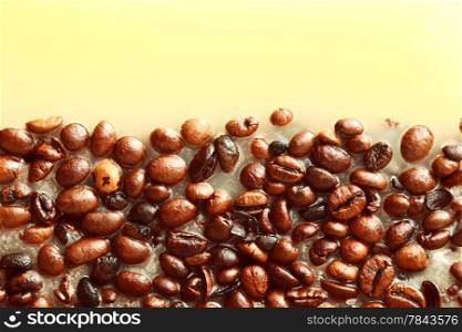 Coffee beans in yellow wax as background with space for text