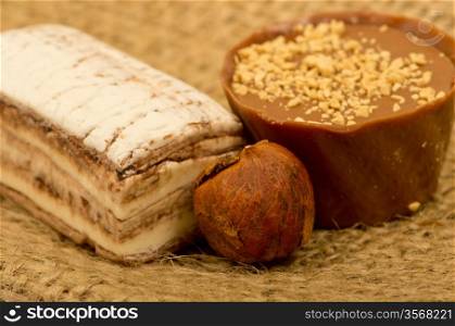 coffee beans, nuts and sweet on burlap background, focused on nuts