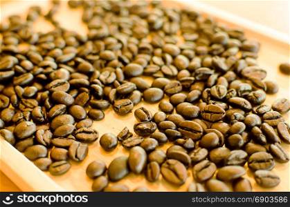 Coffee beans on a wooden tray.