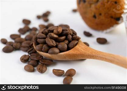 Coffee beans on wooden spoon and Banana Cupcakes on a white wood table.