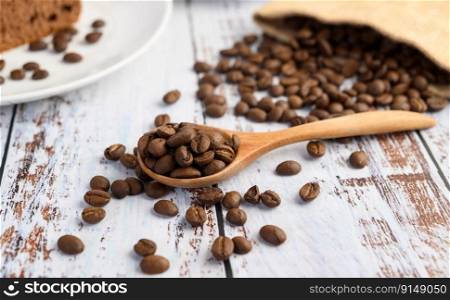 Coffee beans on wooden spoon and hemp sacks on a white wood table.