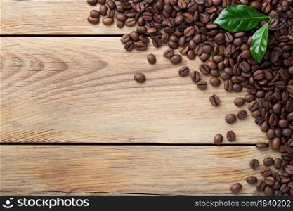 Coffee beans on wooden table background with green leaves. Copy space. Top view. Coffee Beans On Wooden Table Background