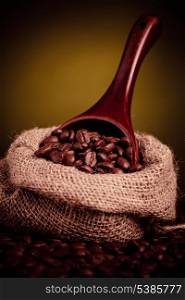 coffee beans spilling out of wooden scoop with copy space