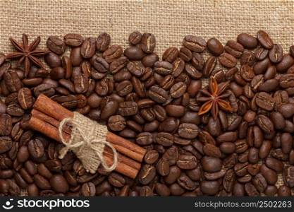 Coffee beans with cinnamon sticks and anise stars on sack cloth background