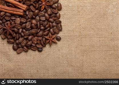 Coffee beans with cinnamon sticks and anise stars on sack cloth background with copy space