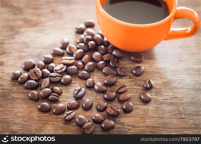 Coffee beans with coffee cup on wooden table, stock photo