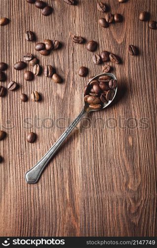 Coffee beans with metal spoon on wooden background. Coffee beans with metal spoon