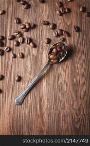 Coffee beans with metal spoon on wooden background. Coffee beans with metal spoon