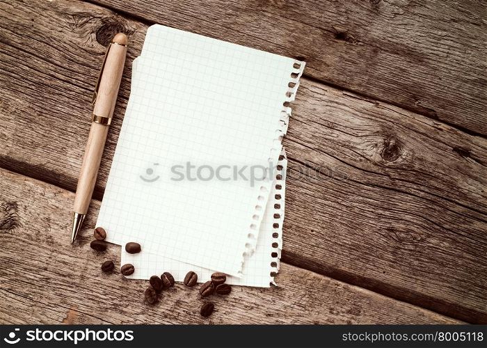 Coffee beans with notebook and pen on wood background