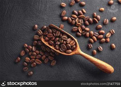 Coffee beans with wooden scoop on black textured background. Coffee beans with wooden scoop