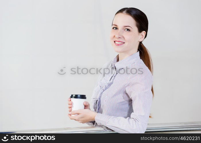 Coffee break. Casual caucasian woman standing at balcony with coffee in hands