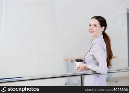Coffee break. Casual caucasian woman standing at balcony with coffee in hands