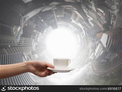 Coffee break. Close up of hand holding white cup of tea or coffee