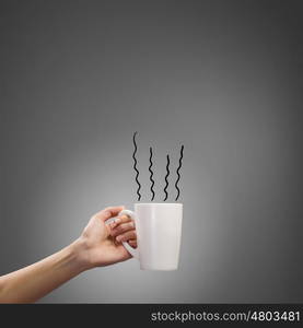 Coffee break. Close up of hand holding white mug of tea or coffee