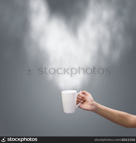 Coffee break. Close up of hand holding white mug of tea or coffee