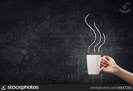 Coffee break. Close up of hand holding white mug of tea or coffee