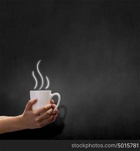 Coffee break. Close up of hand holding white mug of tea or coffee