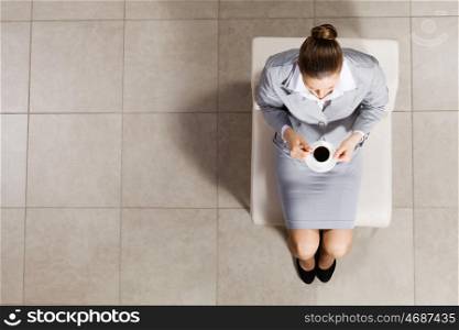 Coffee break. Top view of busineswoman sitting on chair with cup of coffee