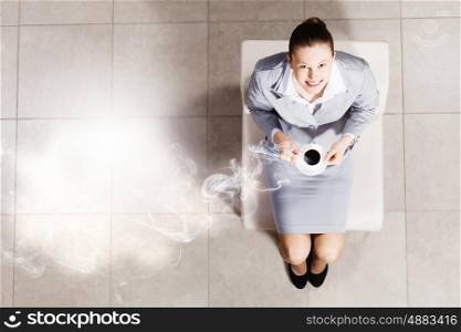 Coffee break. Top view of busineswoman sitting on chair with cup of coffee