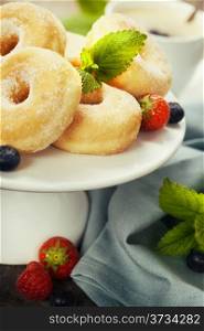 Coffee break with fresh berries and sugary donuts over white background