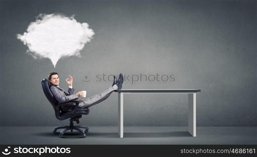 Coffee break. Young businessman sitting in chair with cup in hands