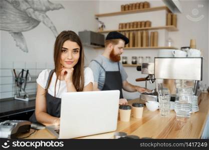 Coffee Business Concept - beautiful caucasian bartender barista or manager working and planing in laptop at modern coffee shop.