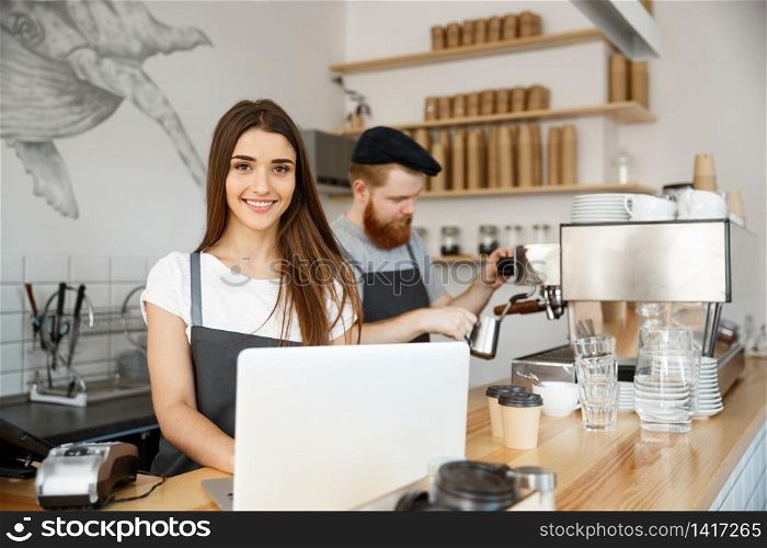 Coffee Business Concept - beautiful caucasian bartender barista or manager working and planing in laptop at modern coffee shop.