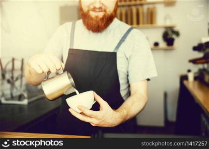 Coffee Business Concept - handsome bearded man in apron making coffee while standing at cafe.. Coffee Business Concept - handsome bearded man in apron making coffee while standing at cafe