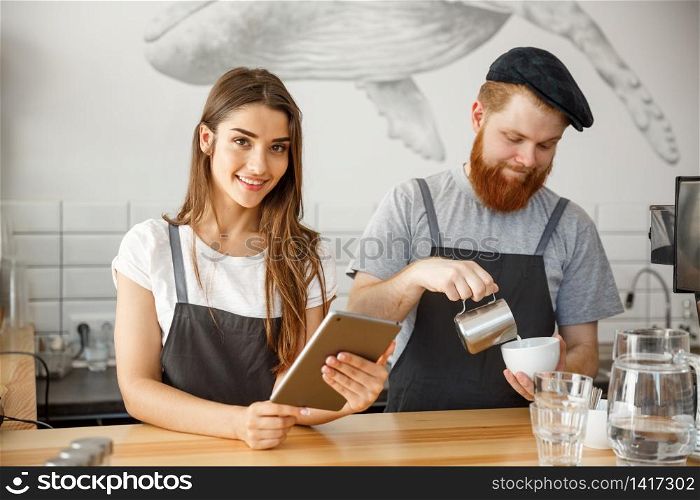 Coffee Business Concept - happy young couple business owners of small coffee shop working and planing on tablet.