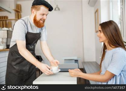 Coffee Business Concept - Waiter or bartender serving hot coffee and talking with caucasian beautiful lady in blue dress at Coffee shop.
