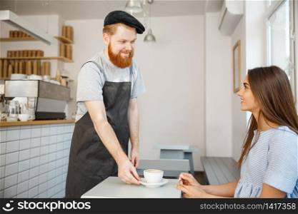 Coffee Business Concept - Waiter or bartender serving hot coffee and talking with caucasian beautiful lady in blue dress at Coffee shop.