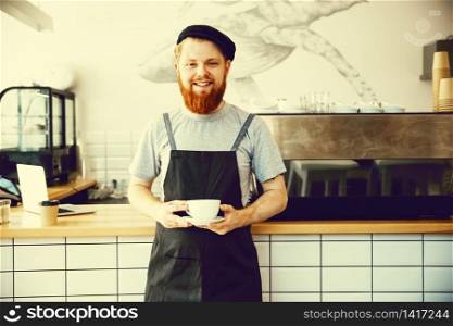 Coffee Business owner Concept - Portrait of happy young bearded caucasian barista in apron with confident looking and smiling to camera in coffee shop counter. Coffee Business owner Concept - Portrait of happy young bearded caucasian barista in apron with confident looking and smiling to camera in coffee shop counter.