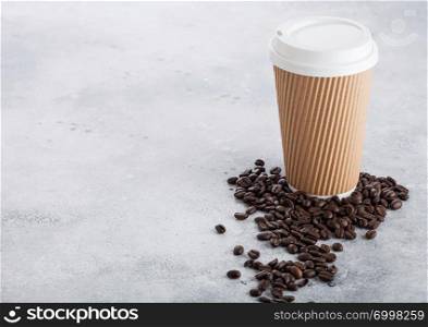 Coffee cardboard cup with fresh coffee beans on stone kitchen background. Brown color.