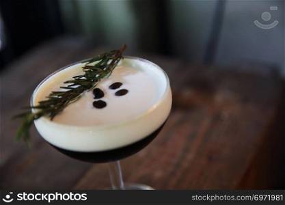 Coffee cocktail with coffee bean and rosemary on top with wood background