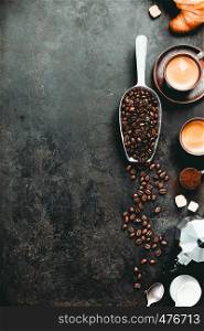 Coffee composition on dark background. Coffee espresso in dark cups, coffee beant, ground coffee, brown sugar, milk, croissants, capsules. Food frame concept. Flat lay. Coffee espresso in dark cups, coffee beant, ground coffee, brown sugar, milk, croissants, capsules.