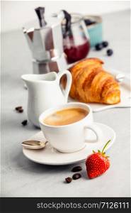 Coffee composition on white concrete background. Coffee espresso in white cup with milk, jam and croissants. Breakfast concept