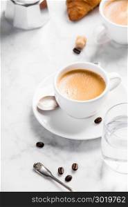 Coffee composition on white marble background. Coffee espresso in white cups with water and croissants. Breakfast concept