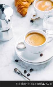 Coffee composition on white marble background. Coffee espresso in white cups with water and croissants. Breakfast concept. Coffee composition on white marble background. Coffee espresso in white cups