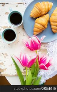 coffee, croissants and three beautiful pink tulips on old white table.. coffee, croissants and three beautiful pink tulips on old white table