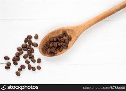 Coffee crop beans on a spoon and wooden background